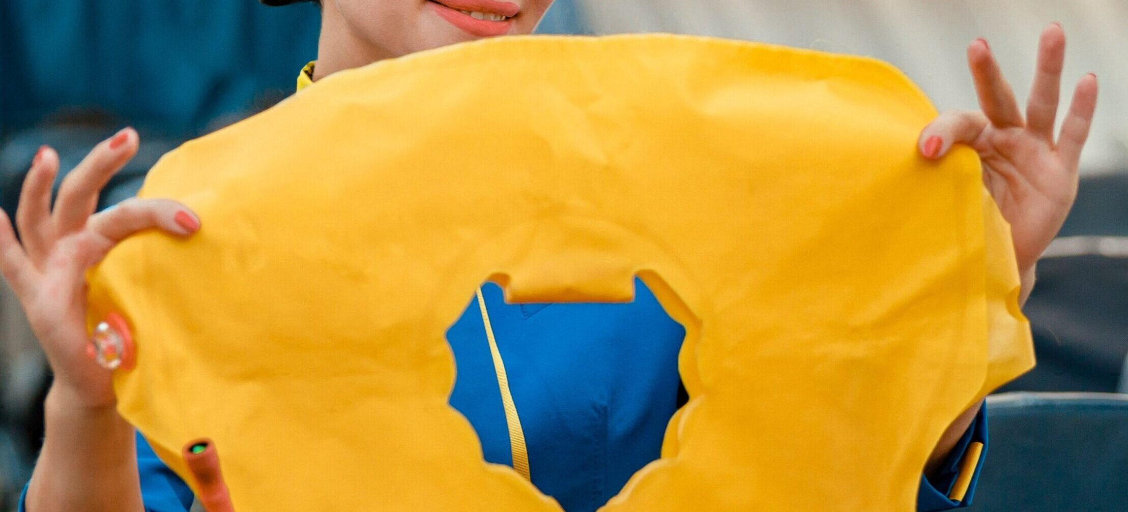 A flight attendant in a blue uniform demonstrating how to use a bright yellow inflatable life vest inside an airplane cabin.